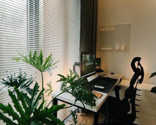 Home office setup with window blinds partially closed filtering strong sunlight